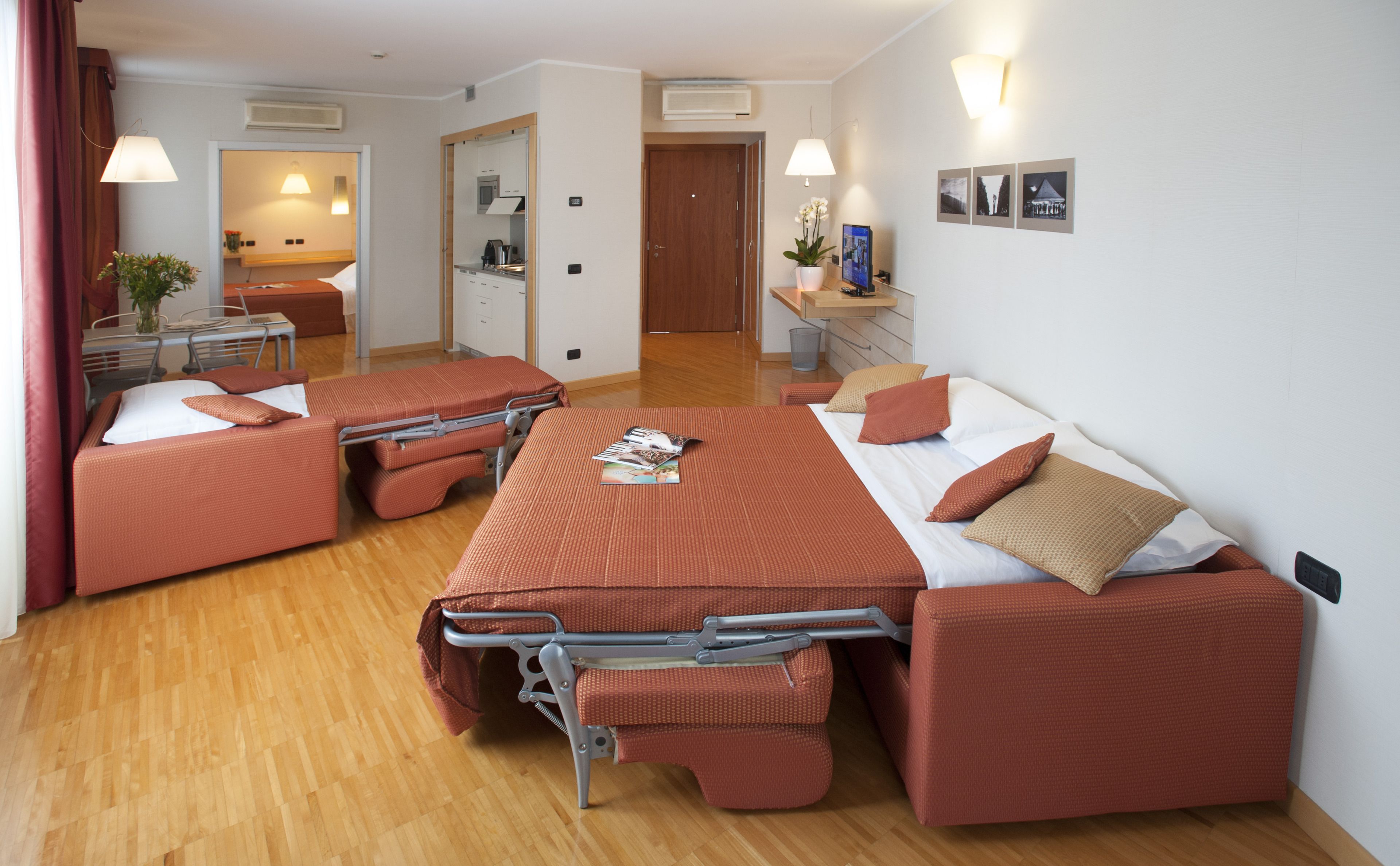 Una habitación de hotel compacta con una cama, un escritorio pequeño y una kitchenette.