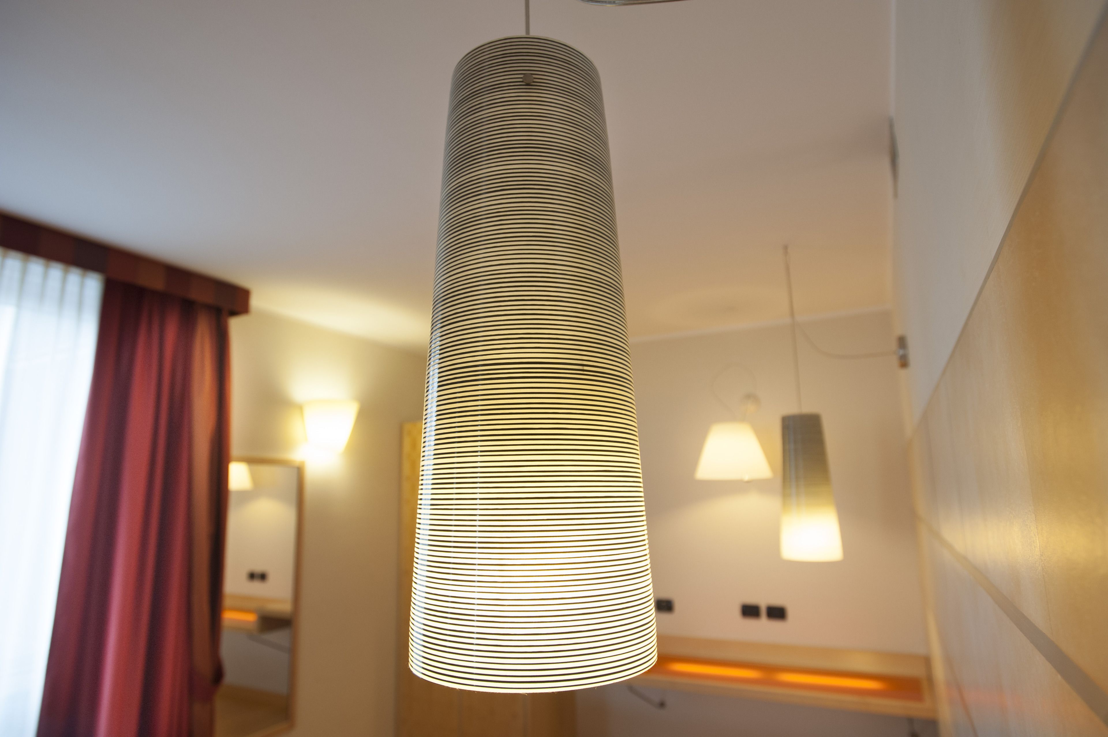 Un luminaire suspendu moderne, de forme cylindrique, installé dans le couloir d’un hôtel.