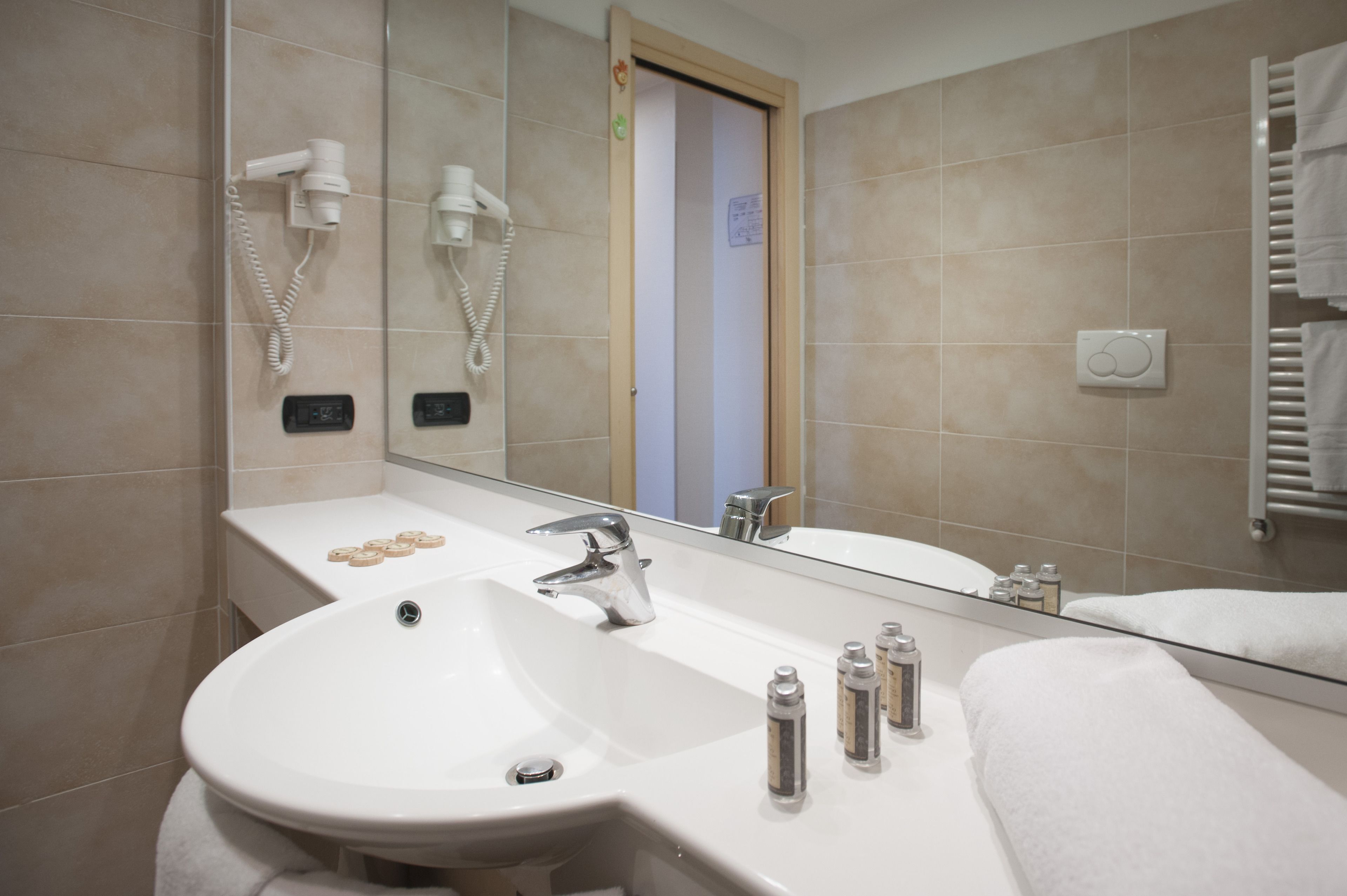 A modern bathroom with a large sink, a mirror, a towel rack, and a hairdryer.