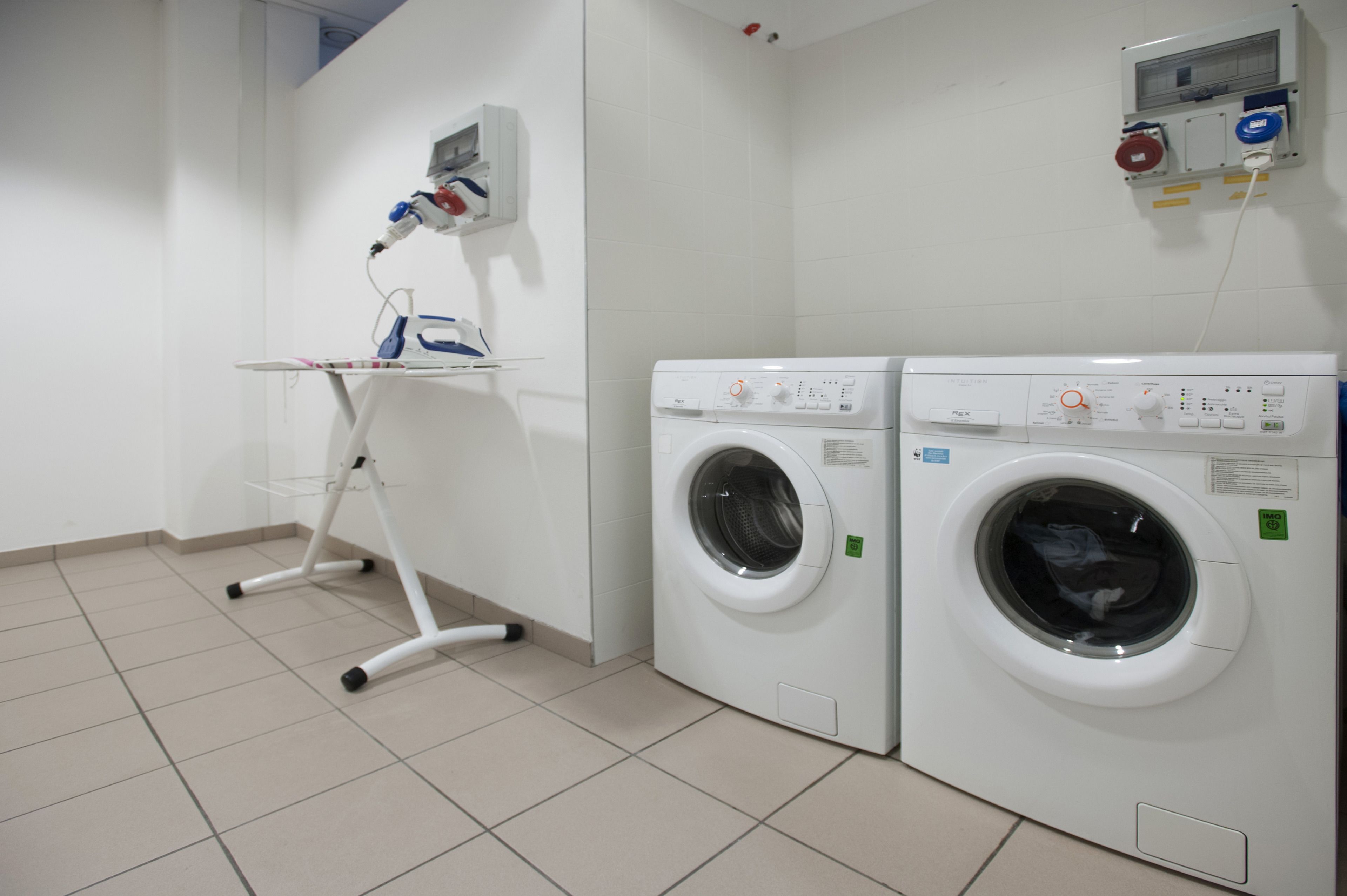 A laundry area with two washing machines and a drying rack.