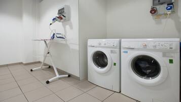 A laundry area with two washing machines and a drying rack.
