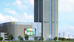 Un edificio moderno de gran altura con un diseño vertical llamativo, un cartel grande que anuncia 'Avatar' y una masa de agua al frente.