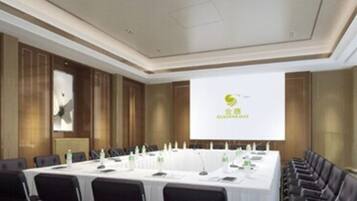 Ein Konferenzraum mit langem Tisch, Stühlen und einer Projektionsleinwand, auf der ein Logo zu sehen ist.