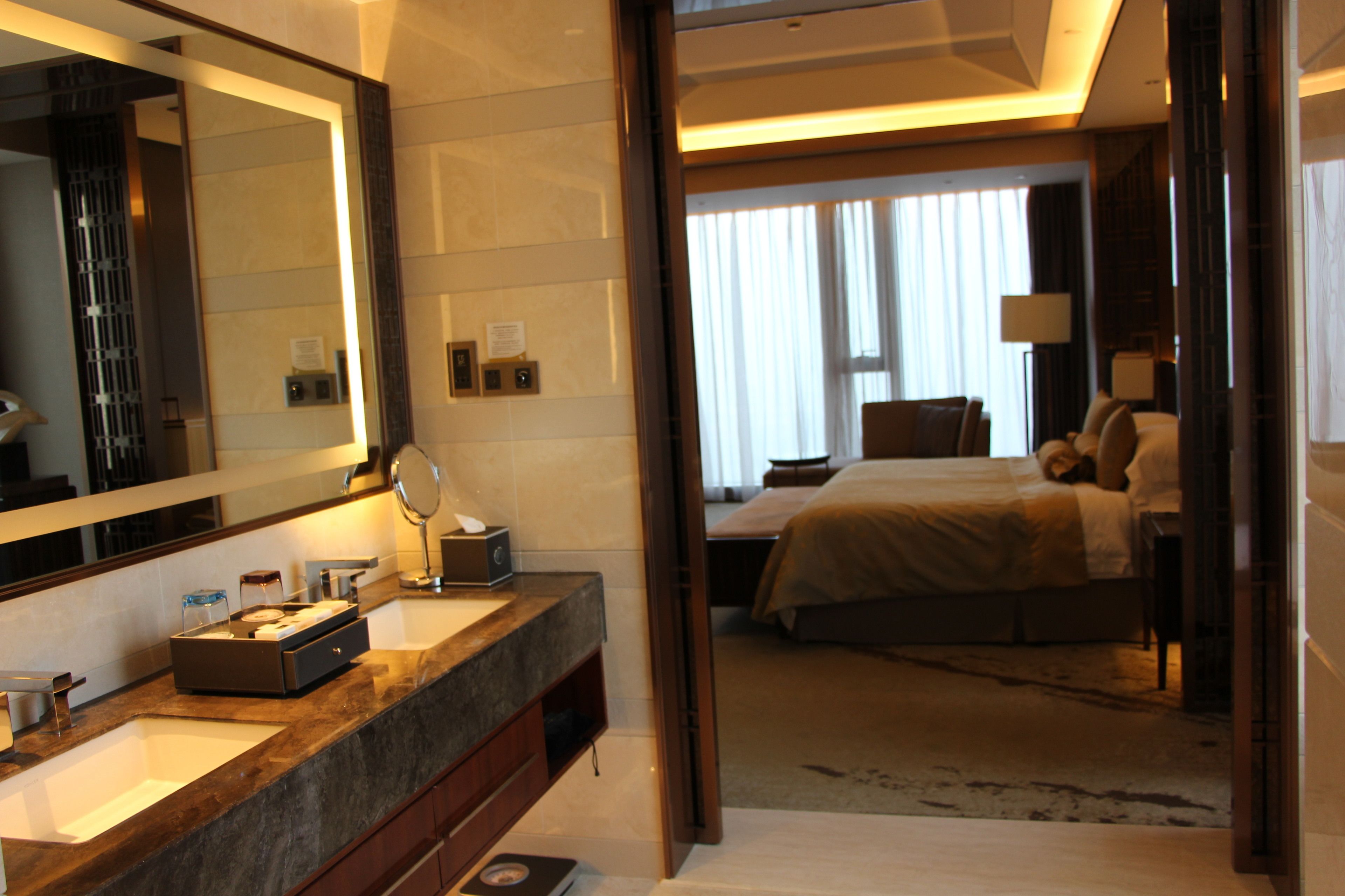 A hotel bathroom with a large mirror, sink, and vanity.