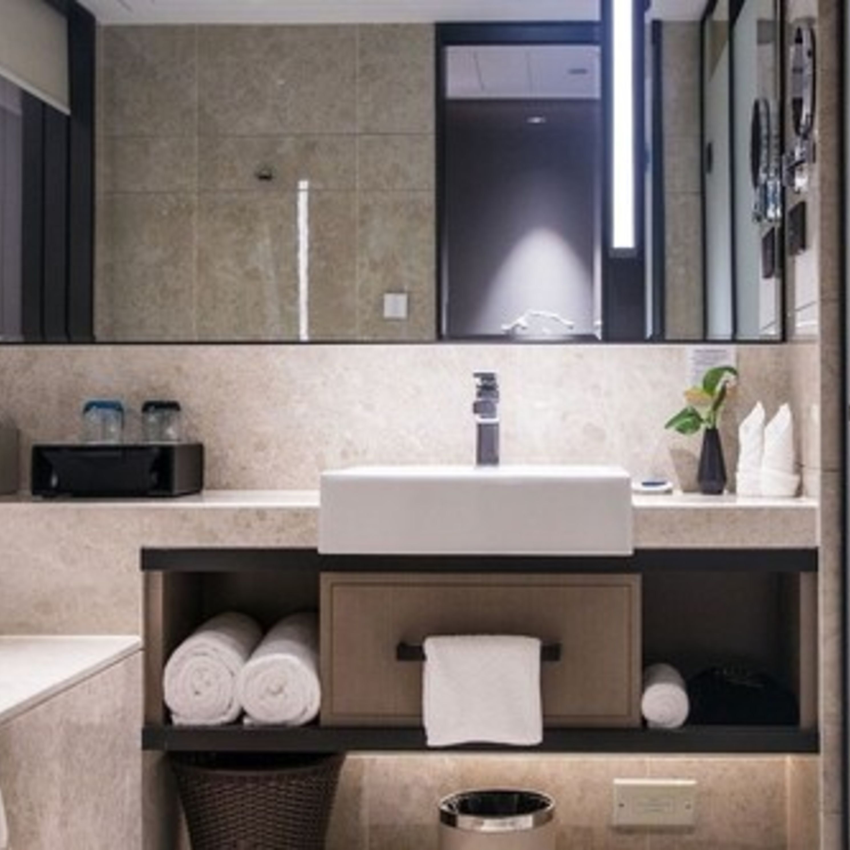 A modern bathroom with a large mirror, a sink, and shelves with towels and toiletries.