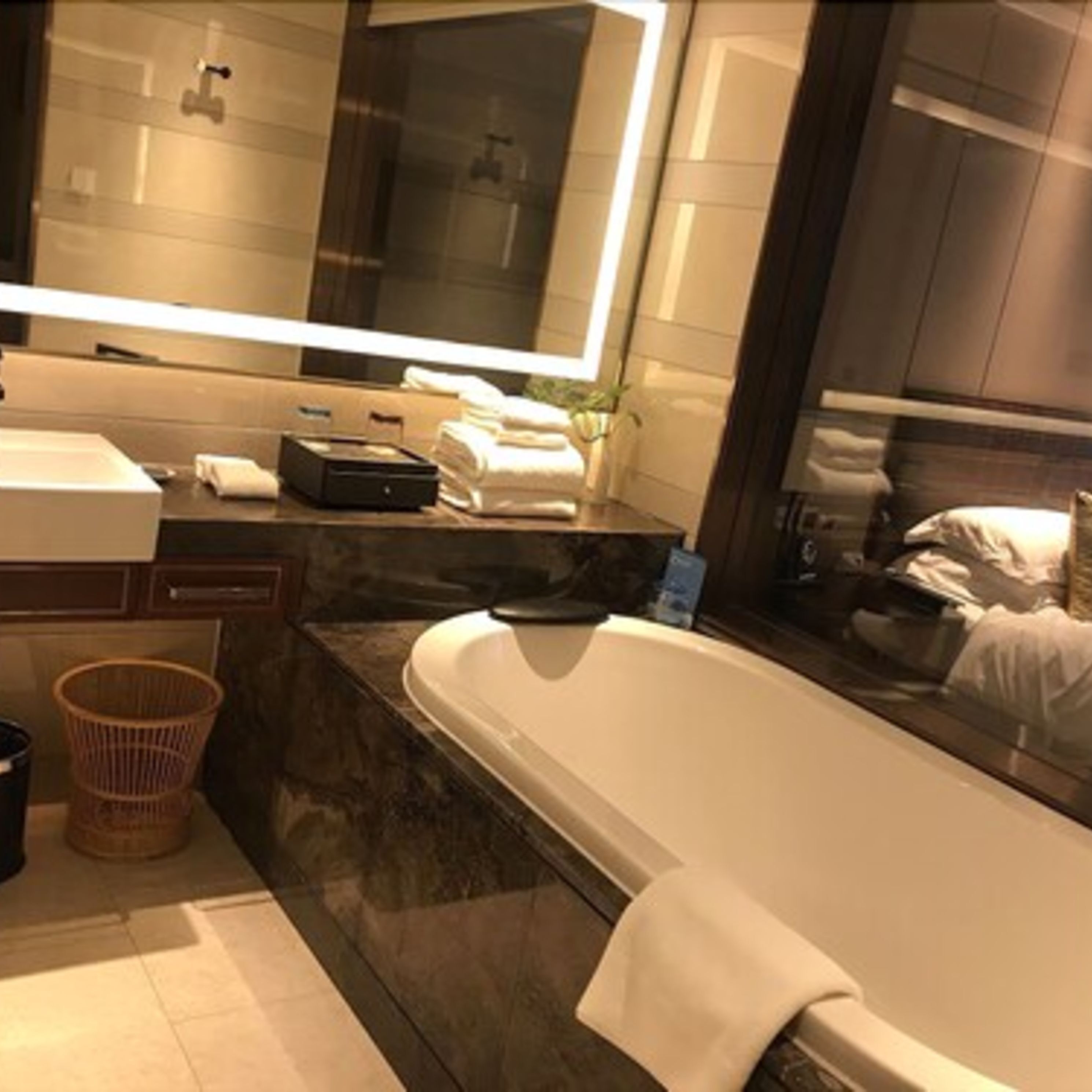 Une salle de bain moderne avec un grand miroir, une baignoire, un lavabo et un meuble-lavabo.