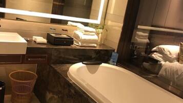 Une salle de bain moderne avec un grand miroir, une baignoire, un lavabo et un meuble-lavabo.