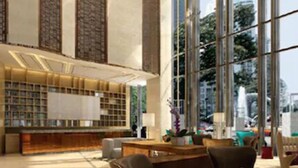 Un lobby amplio con mostrador de recepción, zona de estar y ventanas grandes que ofrecen vistas de la ciudad.