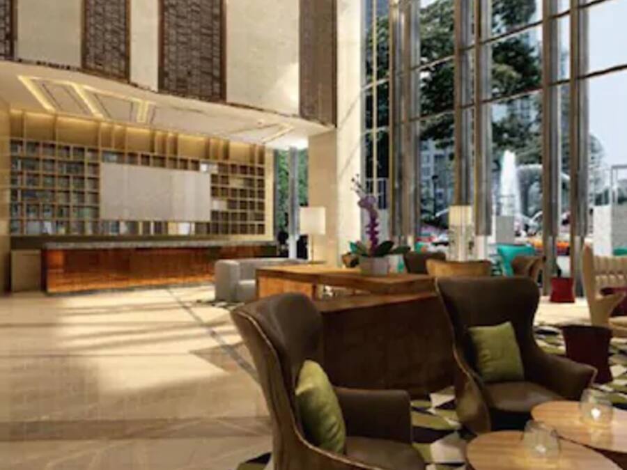 Un lobby amplio con mostrador de recepción, zona de estar y ventanas grandes que ofrecen vistas de la ciudad.