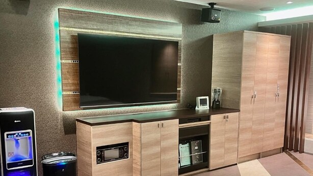 Ein modernes Wohnzimmer mit großem Flachbildfernseher, integriertem Entertainment-System und einer Holzkabine.