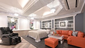 Ein modernes Zimmer mit Massagesessel, Bett, Sofa und Massagetisch.