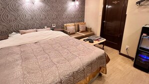 Ein Hotelzimmer mit einem großen Bett, einer Schlafcouch, einem Schreibtisch und einer Tür.