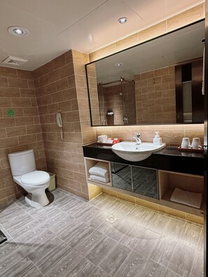 Un baño moderno con inodoro, lavamanos y espejo.