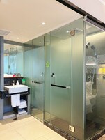 A modern bathroom with a glass-enclosed shower, a sink with a marble countertop, and a towel rack.
