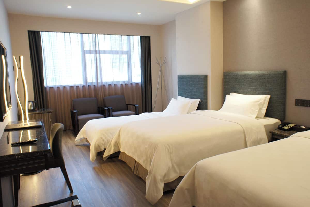 A hotel room with two beds, a desk with a telephone, and a chair.
