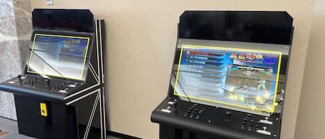 Dos máquinas de videojuegos arcade en una sala con suelo de madera y pared de mármol.