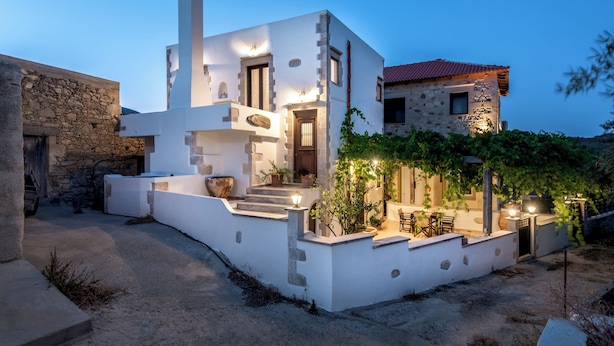 A modern white building with a stone wall, a chimney, and a red-tiled roof. - Villa Aerino (Kissamos)