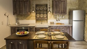 A kitchen with dark wooden cabinets, a central island with a bowl of fruit, and a built-in wine rack above the sink. - Villa Aerino (Kissamos)