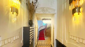 A grand hallway with a red carpet, ornate wall sconces, and a staircase with a red carpet leading to a room. - 7th Heaven Vienna Center Apartments (Vienna)