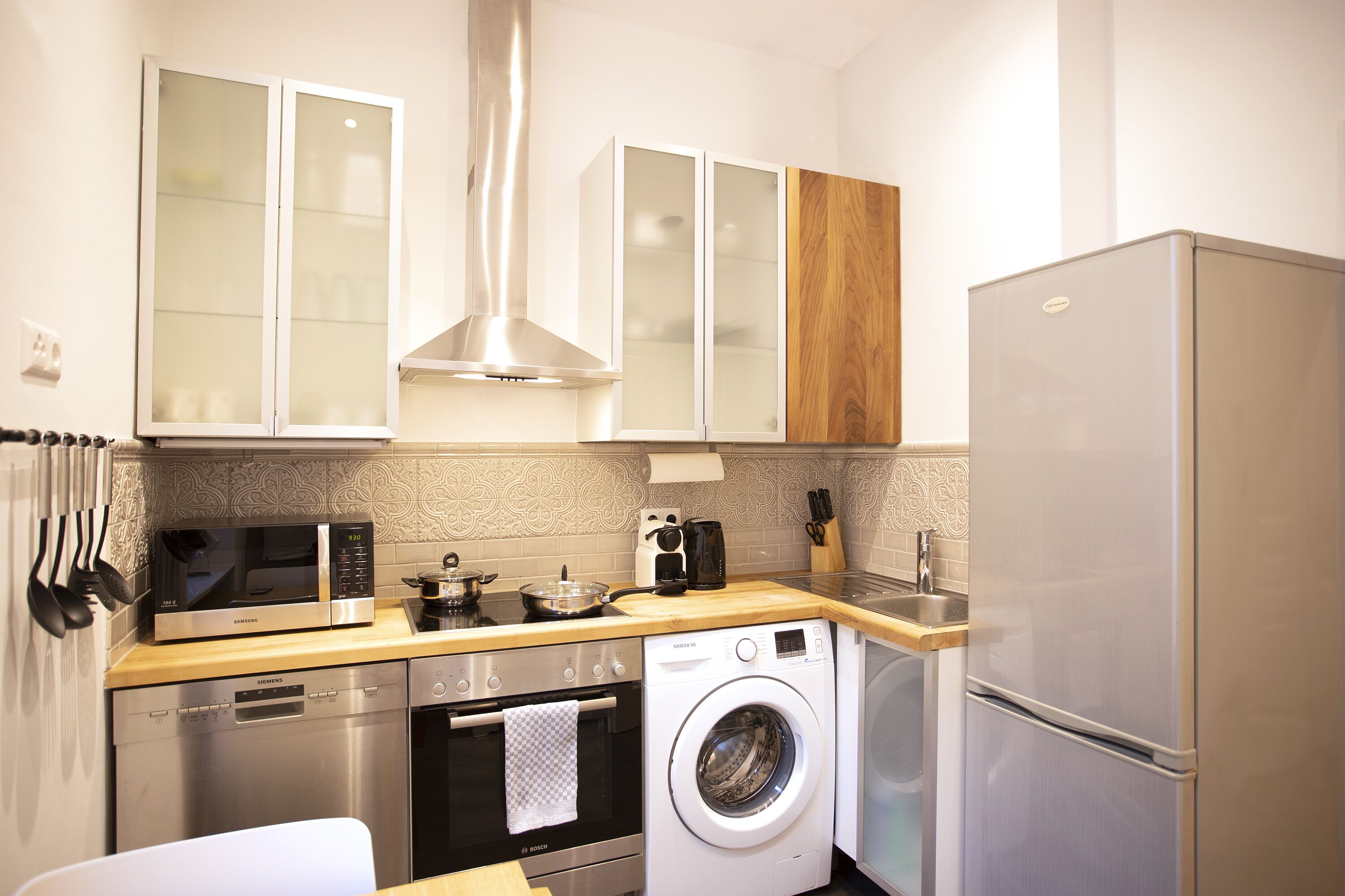 A compact kitchen with a microwave, toaster, sink, dishwasher, and washing machine.