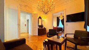 A spacious living room with a chandelier, a sofa, a table, and a television. - 7th Heaven Vienna Center Apartments (Vienna)