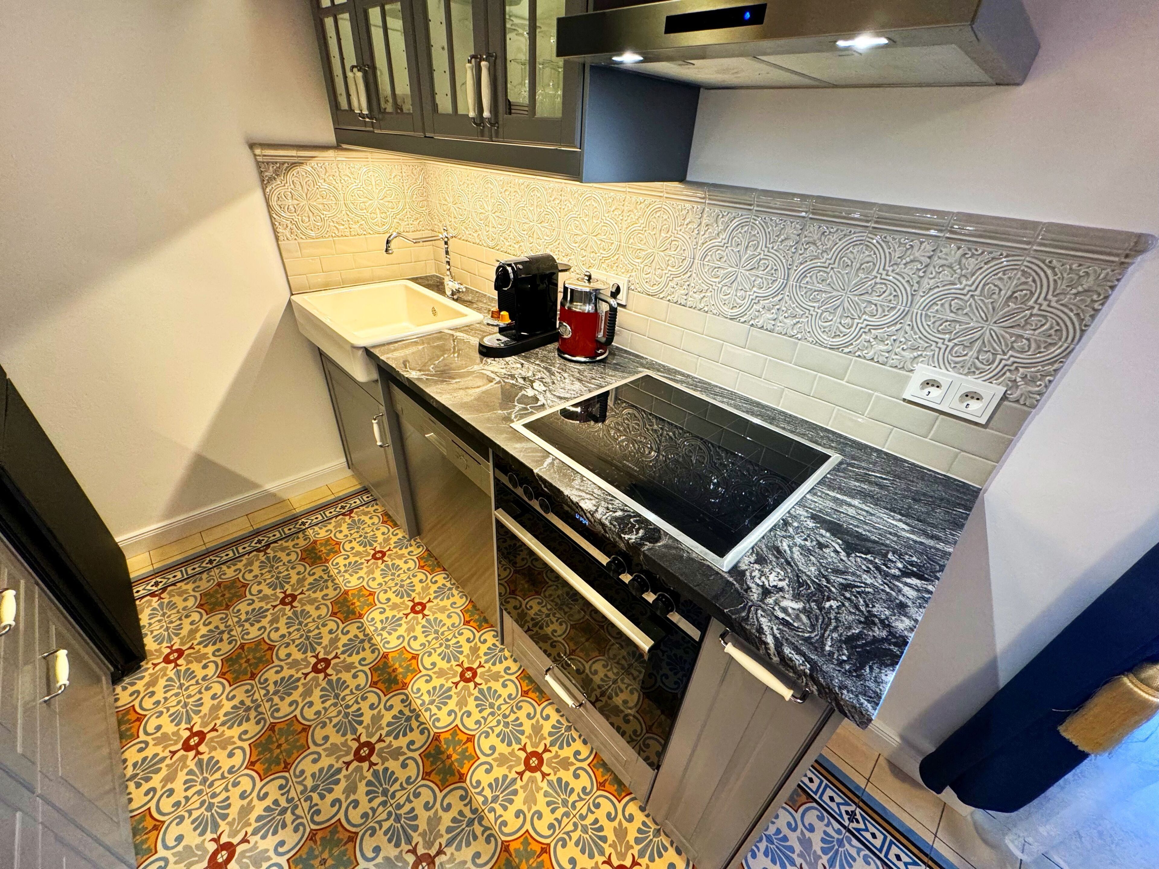 Een kleine keuken met een spoelbak, fornuis en koffiezetapparaat.