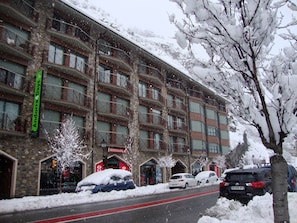 Ein mehrstöckiges Hotel mit Balkonen, eine schneebedeckte Straße und abgestellte Autos.
