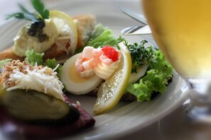 Prato de comida com camarões, uma fatia de limão e um copo de vinho branco.
