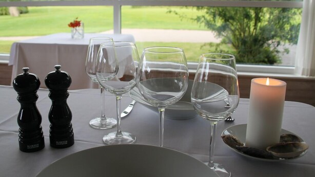 A table set for dining with salt and pepper shakers, wine glasses, and a candle. - Blokhus Golfcenter (Pandrup)