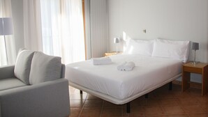 A hotel room with a bed, a chair, a nightstand, and a lamp. - Aptos Colells (Bordes d'Envalira)