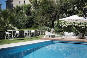 A pool area with a clear blue pool, white lounge chairs, and a pergola with white umbrellas. - La Villa Guy (Béziers)