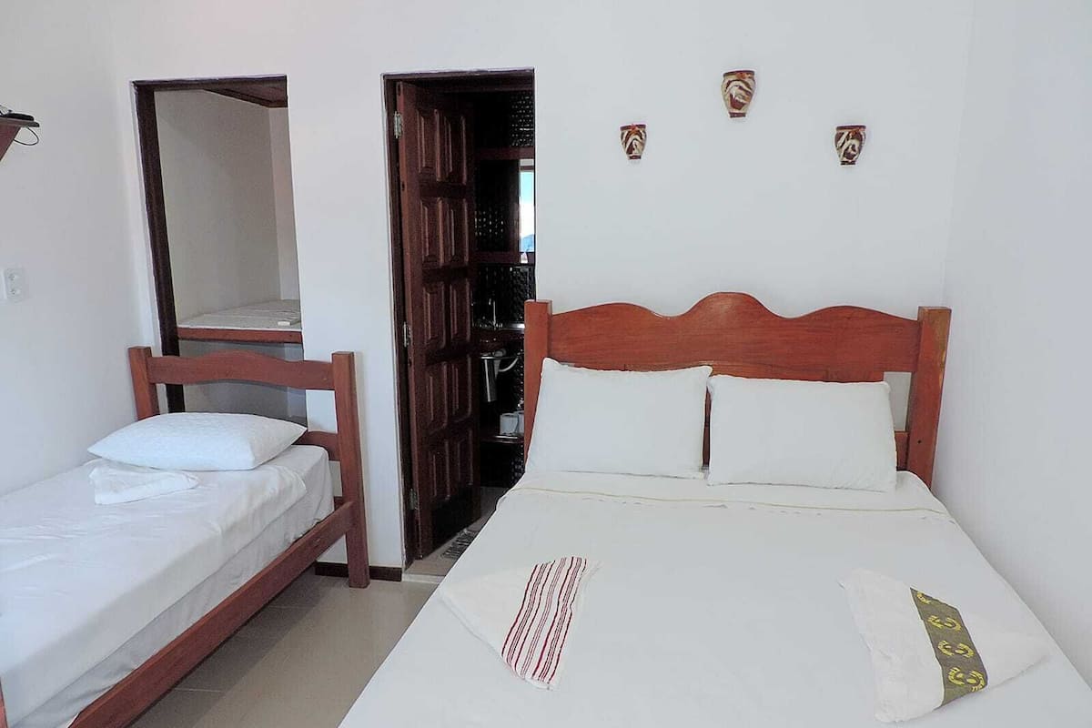 A bedroom with a single bed, a smaller bed, and a wardrobe.
