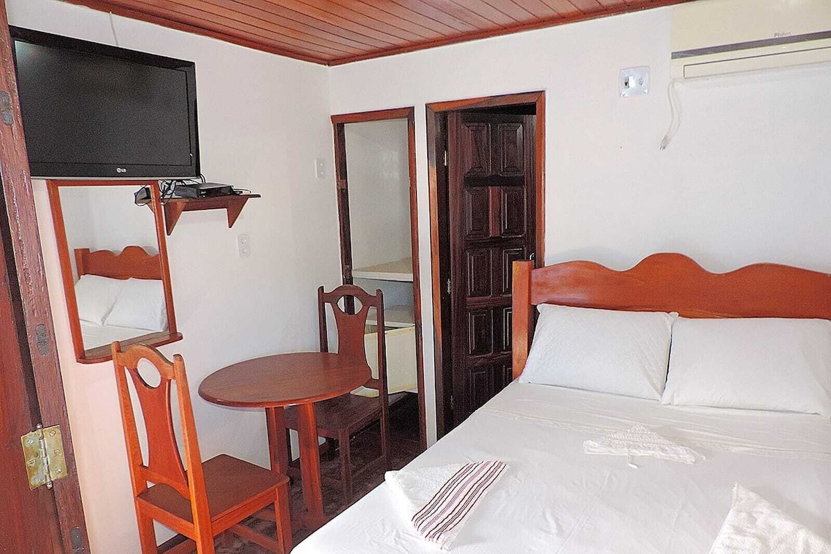 A hotel room with a bed, a TV, a small table, and a chair.