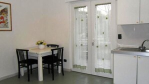 A compact kitchen with white cabinets, a sink, and a dining area with a table and chairs. - Le Sorbole (Matera)