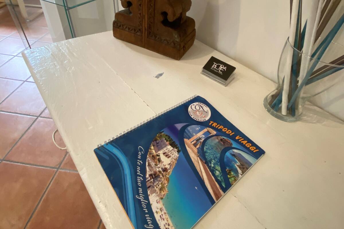 A table with a book titled 'TRIPOLI VIAGGI', a lamp, and a small card.