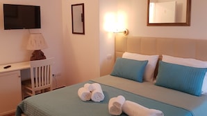 Ein Hotelzimmer mit Bett, Schreibtisch, Stuhl, Fernseher und Spiegel.