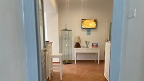 Ein Hotel Eingang mit gefliestem Boden, einem Schreibtisch mit Lampe, einem Fernseher und einer Wanddekoration.