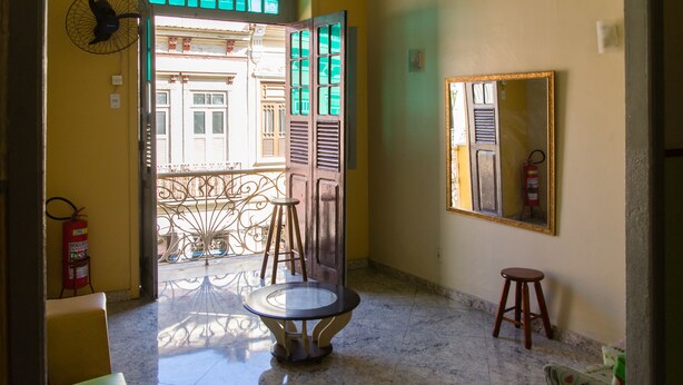 Un pasillo con suelo de mármol, una mesa redonda, dos taburetes, un extintor y un espejo en la pared.
