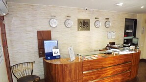 Una mesa de recepción con relojes mostrando diferentes husos horarios, una computadora y un cartel que indica el acceso al garaje.