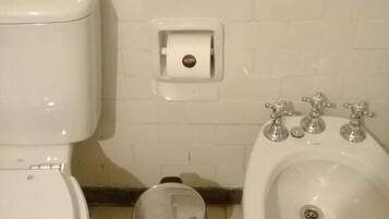Un baño con inodoro, bidé y cubo de basura.