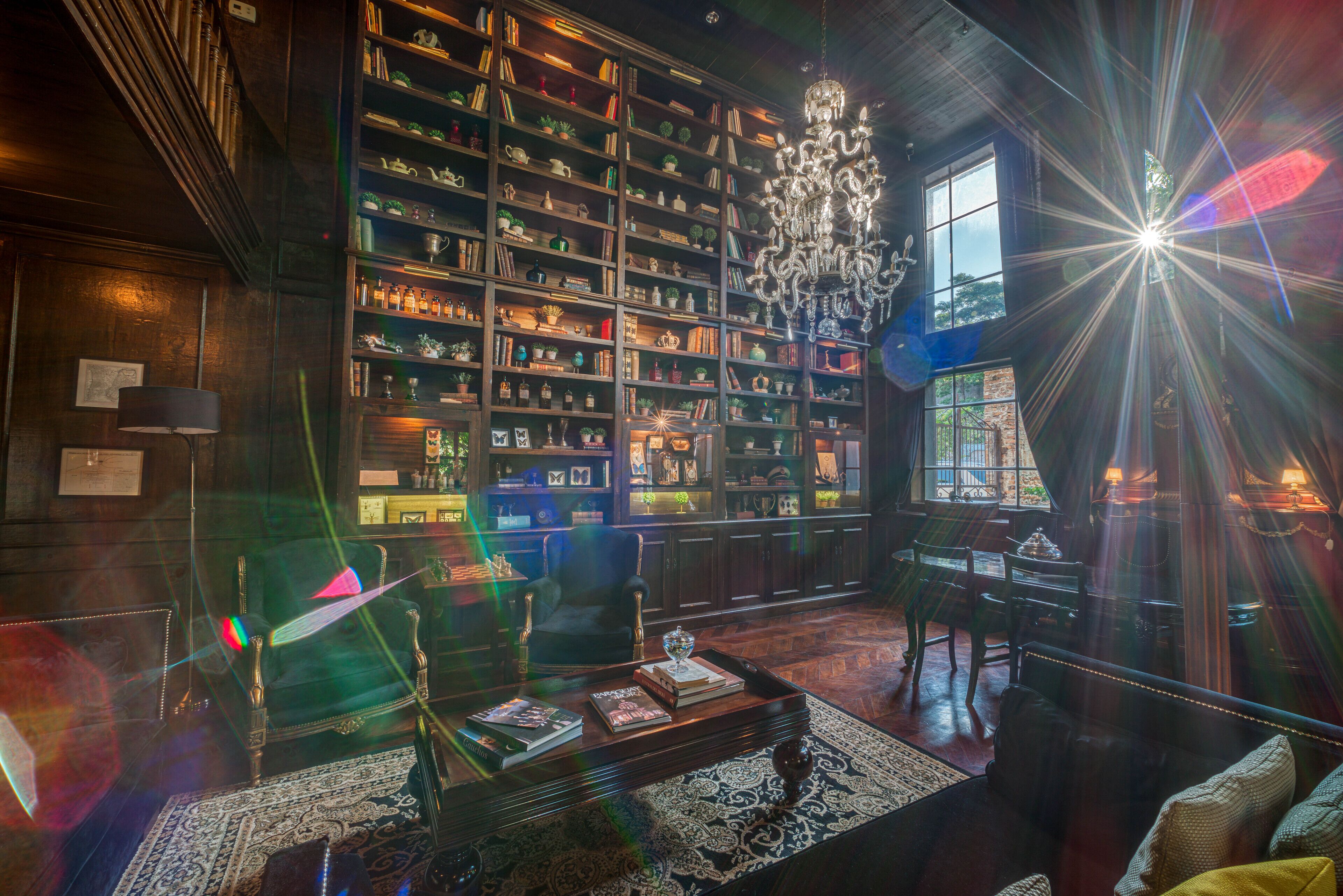 Una biblioteca con estanterías, una araña, un sofá y una mesa de centro.
