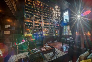 Una biblioteca con estanterías, una araña, un sofá y una mesa de centro.