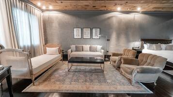 Quarto moderno com teto de madeira, uma cama grande, sofá, mesa de centro e escrivaninha.
