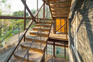 Una escalera de madera de varios niveles con barandillas metálicas que lleva a un piso superior.