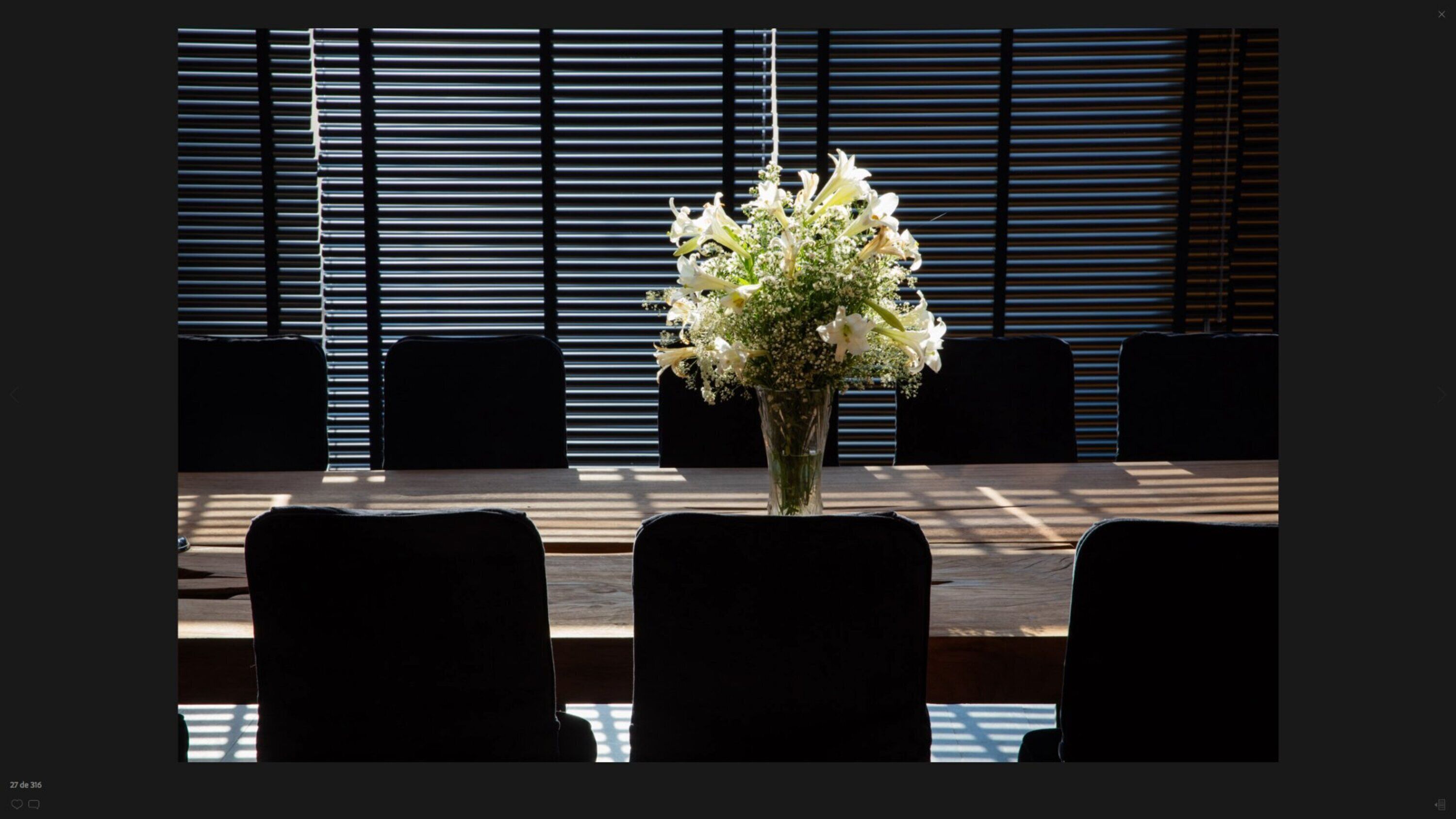 A conference table with a vase of white flowers in the center, surrounded by chairs.