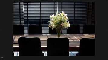 A conference table with a vase of white flowers in the center, surrounded by chairs.