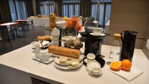 A hotel dining area with a buffet setup, including various dishes, a coffee station, and a decorative centerpiece. - Hotel Forum (Baranzate)