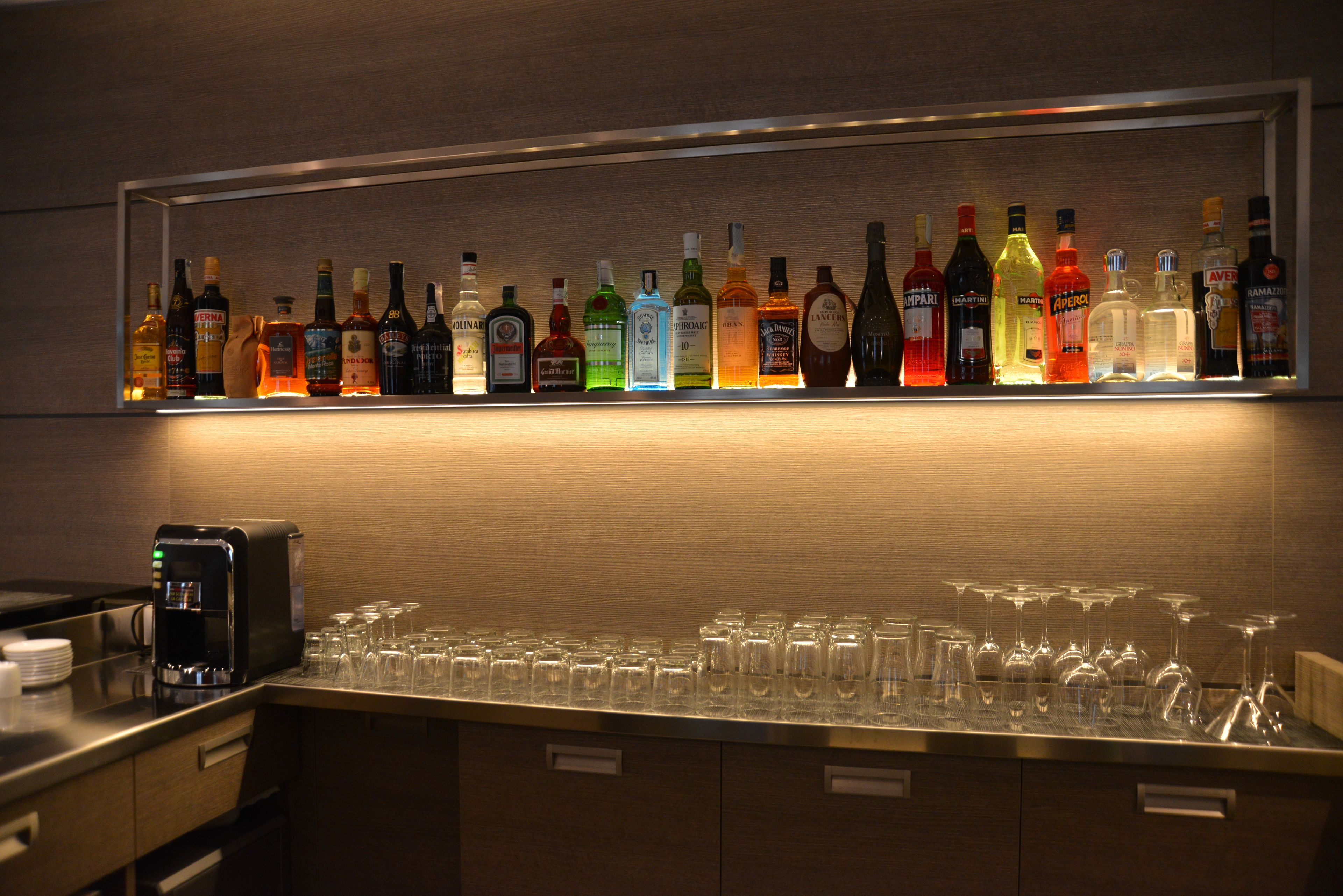 Zona de bar con una variedad de botellas de licor y una máquina de café.