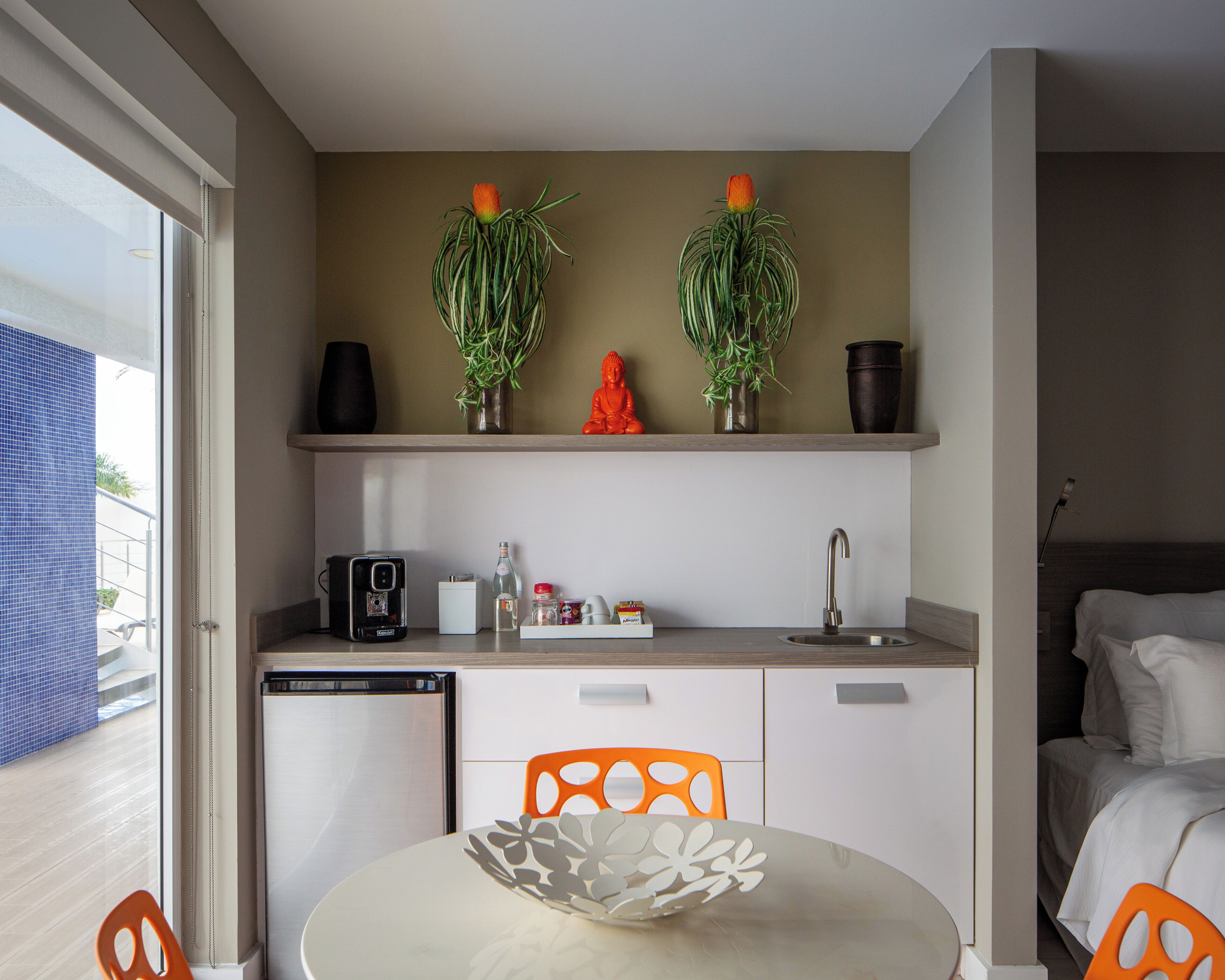 A compact kitchen with a sink, a small refrigerator, and a dining area with a table and chairs.