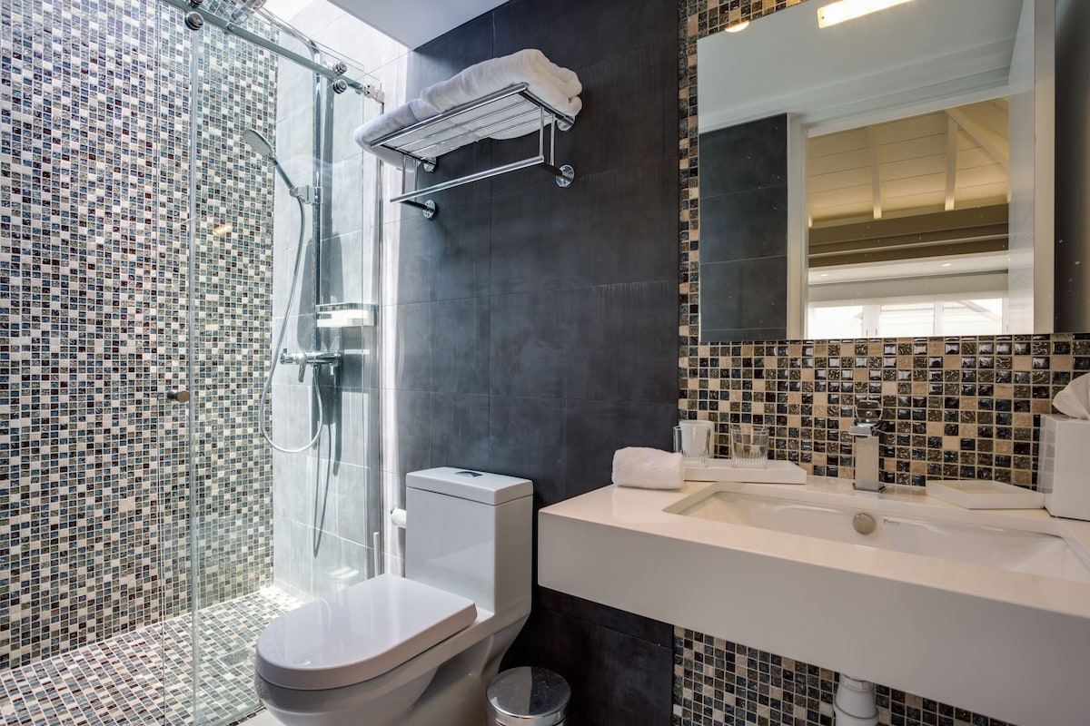 A modern bathroom with a glass shower enclosure, a white toilet, and a sink with a mirror.